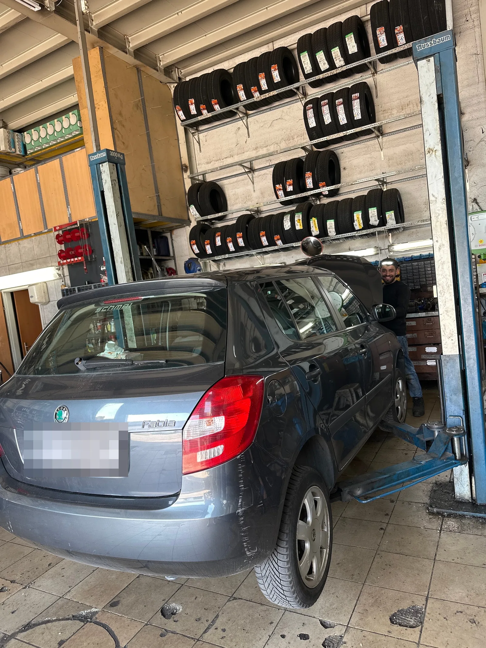 Ein Skoda auf der Hebebühne vor einer Reifenwand