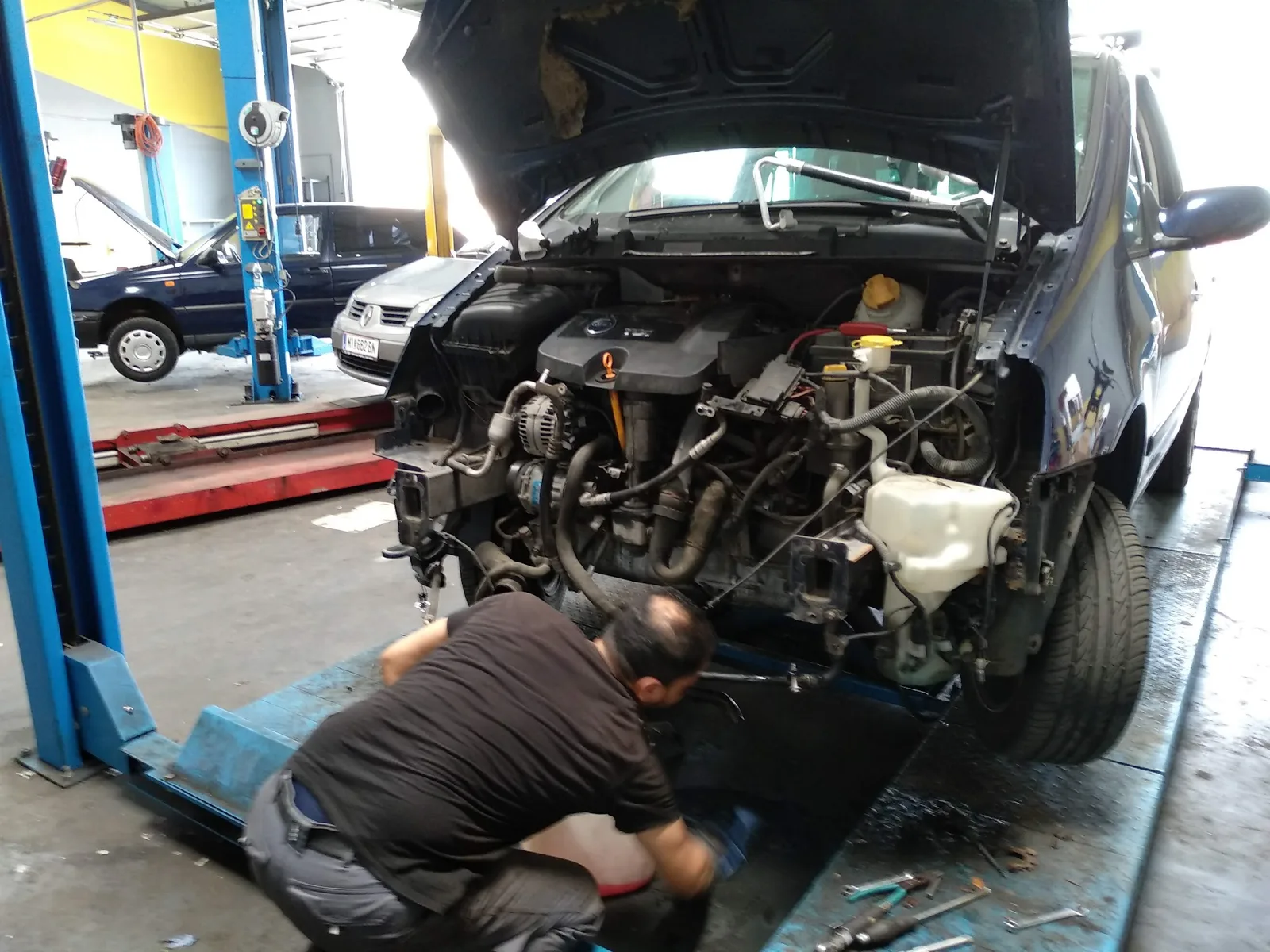 Ein Mechaniker arbeitet am geöffneten Motorraum eines Fahrzeugs
