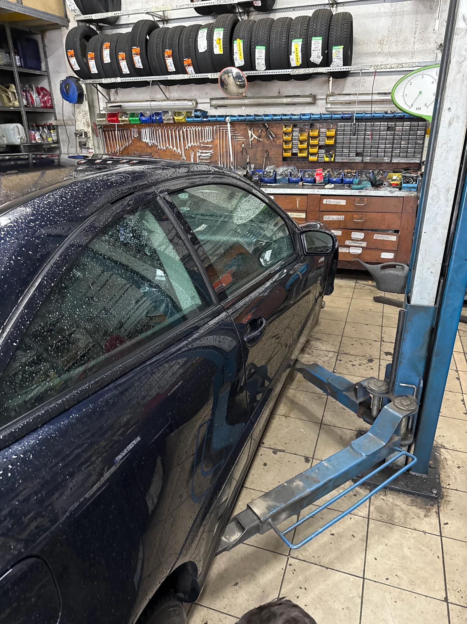 Ein dunkler Wagen auf einer Hebebühne in der Werkstatt