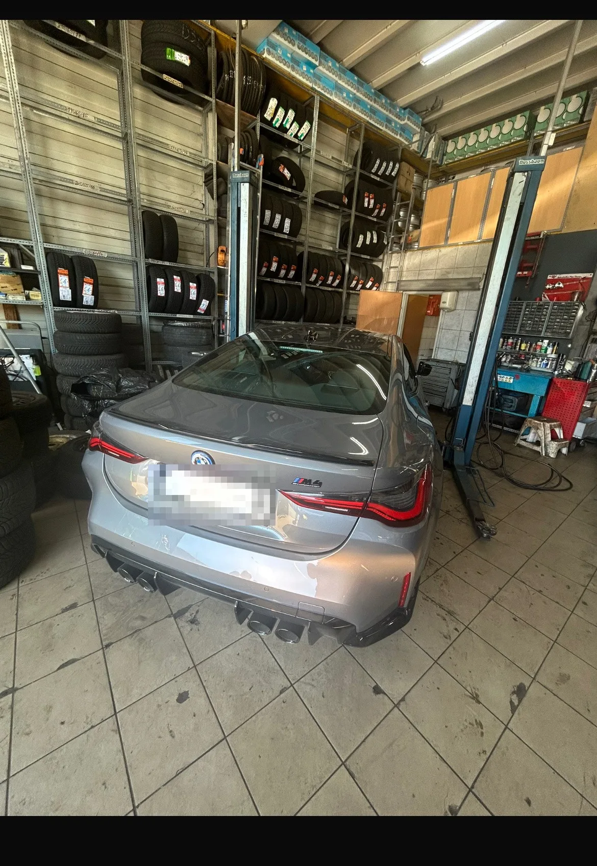 Ein BMW M4 auf der Hebebühne vor Reifenregalen