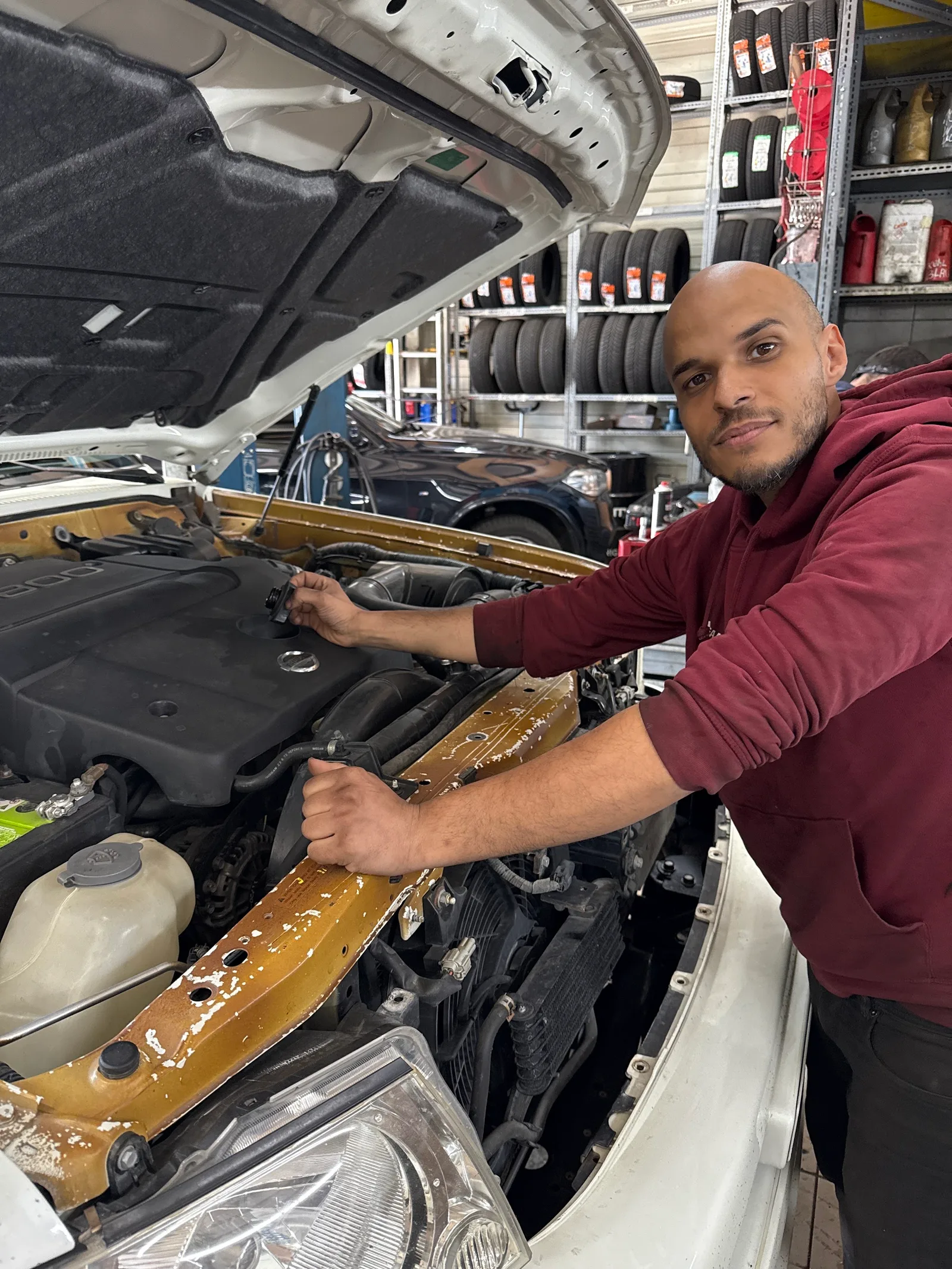 Eine Person arbeitet in der Werkstatt am geöffneten Motorraum